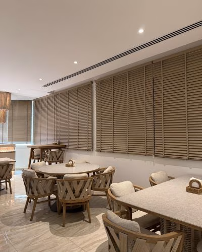 Wooden venetian blinds installed in a Dubai living room — warm natural timber finish